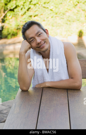 Uomo seduto a tavola sorridente con la testa appoggiata a portata di mano Foto Stock