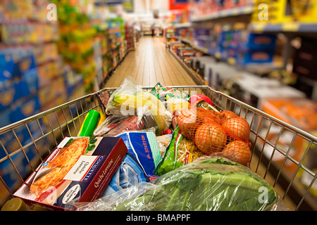 Carrello dello shopping spinto giù supermercato Aisle Wales UK con persona offuscata in background Foto Stock