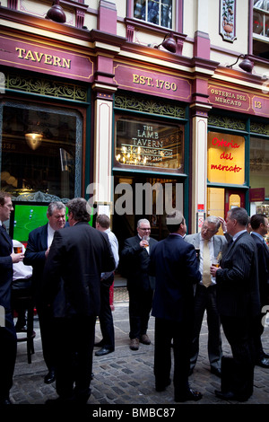 I lavoratori della città mentre sorseggiate un drink al di fuori dell'Agnello Tavern pub nel mercato Leadenhall nella città di Londra. Foto Stock