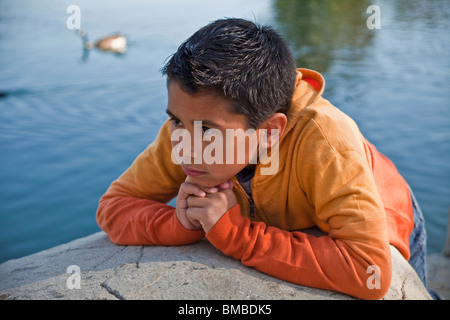 Bambino orante 10-12 anni vecchio ispanica ragazzo americano al di fuori dell ambiente naturale contemplando pensieroso sognando la vita di seduta. Signor © Myrleen Pearson Foto Stock