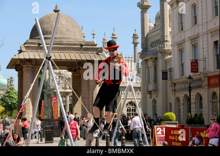 Busker su un funambolico riproduzione di un violino intrattiene la folla nel centro città di Brighton Regno Unito Foto Stock