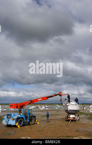 Manutenzione in barca sulla spiaggia con la bassa marea sulla Mersea Island Essex REGNO UNITO Foto Stock
