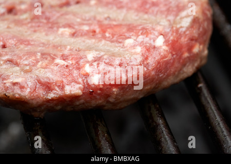 Parzialmente cotto bistecca raw hamburger cottura su un barbeque Foto Stock