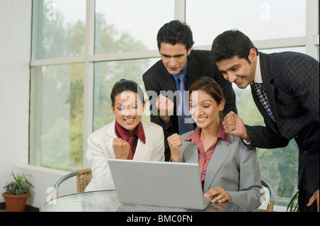 I dirigenti aziendali a celebrare il successo di fronte a un computer portatile Foto Stock