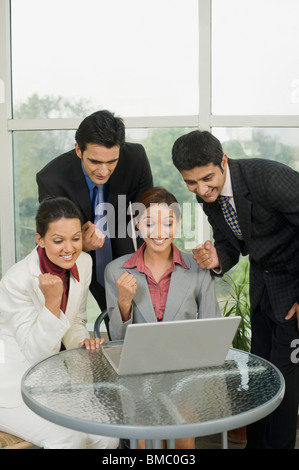 I dirigenti aziendali a celebrare il successo di fronte a un computer portatile Foto Stock
