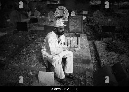 Uomo che prega in una tomba in un cimitero, Vecchia Delhi, India Foto Stock