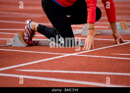 Sulla linea di partenza. Giovane donna si prepara a sprint di successo Foto Stock