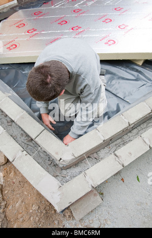 Costruttori adagiarli sotto pavimento isolamento in una casa di estensione in Ambleside, Regno Unito. Foto Stock