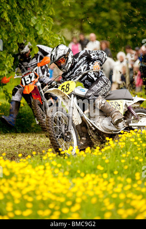 Classic demo di motocross presso la Baronia College open day due moto racing attraverso il campo della molla renoncules vicino a Dumfries Regno Unito Foto Stock