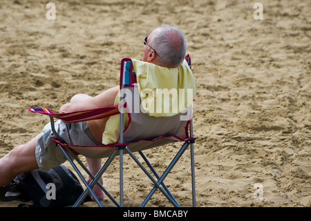Uomo anziano relax su una sdraio sulla spiaggia Foto Stock