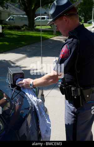 Il Nebraska Trooper stato di pulizia della licenza automatica lettore di piastra che è montata sul suo incrociatore della polizia. Foto Stock