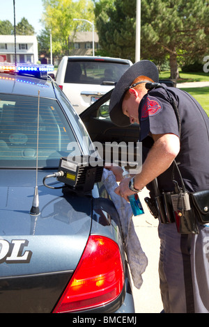 Il Nebraska Trooper stato di pulizia della licenza automatica lettore di piastra che è montata sul suo incrociatore della polizia. Foto Stock