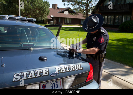 Il Nebraska Trooper stato di pulizia della licenza automatica lettore di piastra che è montata sul suo incrociatore della polizia. Foto Stock