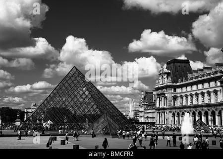 Drammatico in bianco e nero vista panoramica della piramide in vetro e fontane del Louvre bellissimo cielo drammatico Parigi Francia Foto Stock