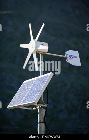 Un solare pannello elettrico e la turbina eolica essendo utilizzata per l'alimentazione di un neon di cartello stradale su Kirkstone Pass, Lake District, UK. Foto Stock