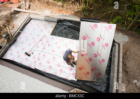 Costruttori adagiarli sotto pavimento isolamento in una casa di estensione in Ambleside, Regno Unito. Foto Stock