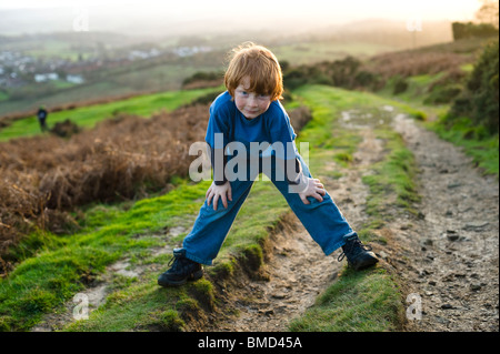 Ragazzo di ridere e giocare mentre passeggiate al tramonto in campagna. Foto Stock