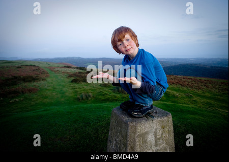 Giovani 6anno vecchio ragazzo in equilibrio su un punto trig al tramonto a Caerphilly Galles del Sud Foto Stock