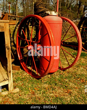 Il gas propano compressore aria vecchio serbatoio rosso su ruote grandi seduto in un campo Foto Stock