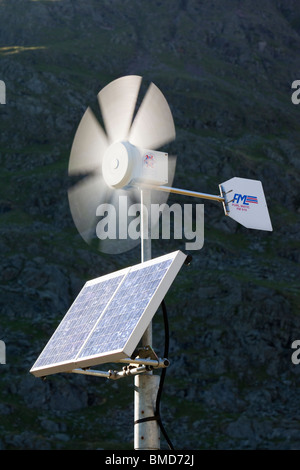 Un solare pannello elettrico e la turbina eolica essendo utilizzata per l'alimentazione di un neon di cartello stradale su Kirkstone Pass, Lake District, UK. Foto Stock