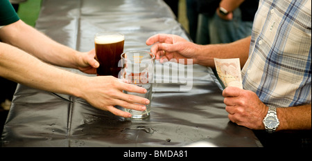 Un cliente che acquista una pinta di real ale all'Hoop Pub festa della birra in magazzino in Essex. Foto Stock