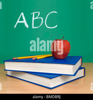 ABC scritto su una lavagna. Libri, matite e un apple sul primo piano. Foto Stock