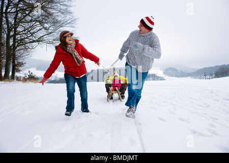 I genitori dei bambini di trazione in slittino in inverno Foto Stock