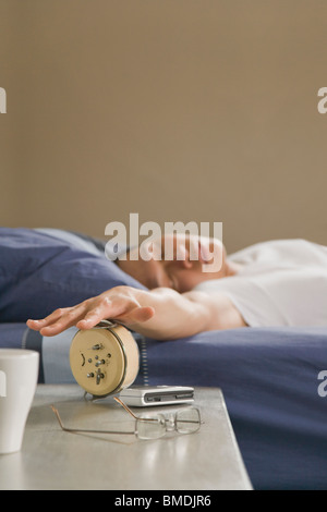 Sleeping Uomo di spegnere la sveglia Foto Stock