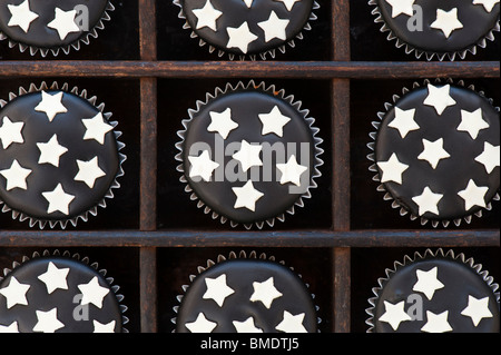 Mini Tortine decorate con glassa di nero e il cioccolato bianco stelle in un vassoio di legno Foto Stock