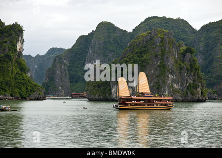 Junk nave accoccolato tra le isole rocciose della baia di Halong, Vietnam Foto Stock