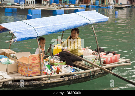 La madre e il bambino di vendita di alimenti e bevande da barca a remi in Halong Bay, Vietnam Foto Stock