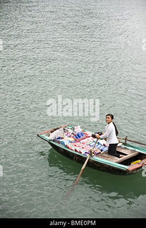 Ragazza giovane di vendita di alimenti e bevande da barca a remi in Halong Bay, Vietnam Foto Stock