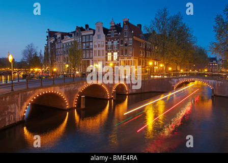 Striature di luce da una nave da crociera di andare sotto i ponti illuminati di Keizersgracht e Leidsestraat Amsterdam Paesi Bassi Foto Stock