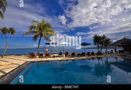 Gli ospiti potrete rilassarvi in piscina di un hotel a Bali, Indonesia. Vista attraverso lo Stretto di Badung a Lombok Foto Stock