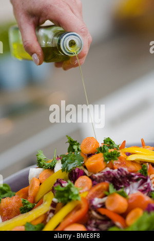 Donna versando olio su verdure, Svezia. Foto Stock