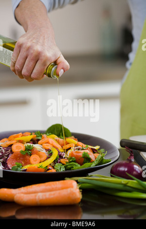 Donna versando olio su verdure, Svezia. Foto Stock