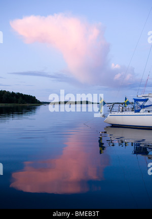 La riflessione di nuvole e la barca in mare Foto Stock