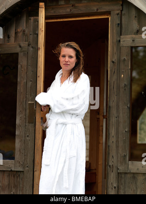 Donna che indossa accappatoio lasciando sauna Foto Stock