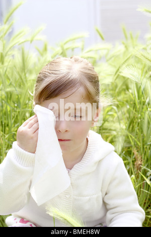 Triste bambina piangere per esterno prato verde di cereali di campo spike erba Foto Stock