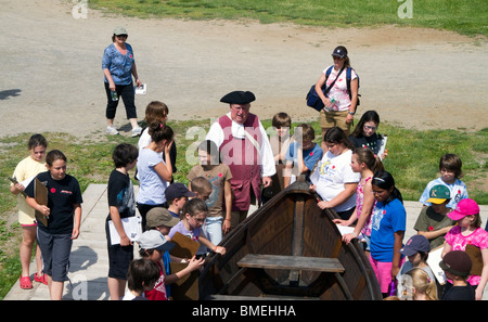 Un periodo vestito in costume a guida Fort Ticonderoga, New York con un gruppo di bambini. Insegnamento e lettura. Foto Stock