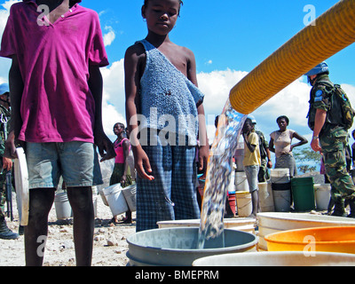 Bambini attendere per acqua potabile, distribuito da peacekeepers delle Nazioni Unite nel semi-deserto al di fuori di Gonaives, Haiti Foto Stock