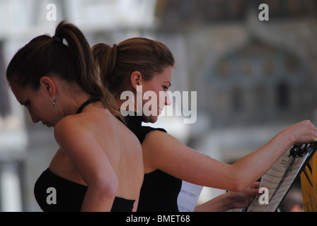 Le donne preparare la riproduzione di un brano in un caffè di Piazza San Marco, Venezia, Italia Foto Stock