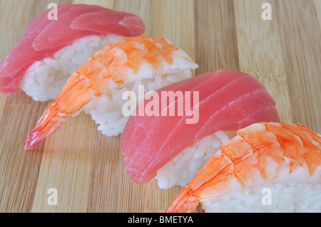 Tonno e gamberetti sushi diagonalmente in fila su di bambù Foto Stock