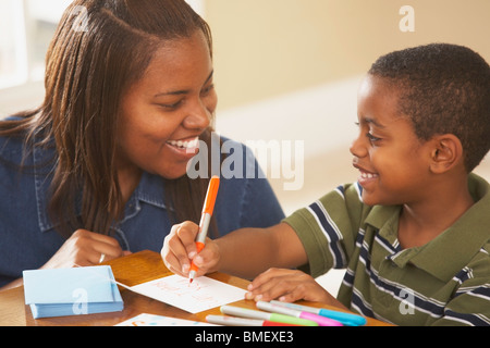 Un ragazzo la scrittura di schede con sua madre Foto Stock