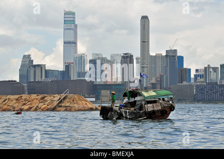 Pescatore, in un cappello di bambù, in piedi sulla prua di un sampan immettendo il Causeway Bay Typhoon Shelter, Hong Kong, Cina Foto Stock