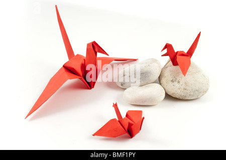 Red Origami gru e i suoi figli su pietre bianche Foto Stock
