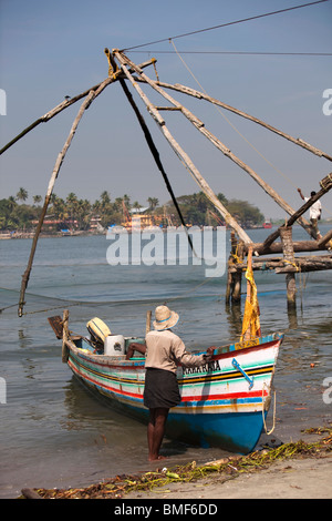 India Kerala, Kochi, Fort Cochin, Cinese reti da pesca, i pescatori con Colorati luminosamente barca Foto Stock