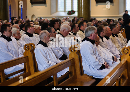 Tanti parroci in seduta i banchi di una chiesa/cattedrale durante la massa Foto Stock