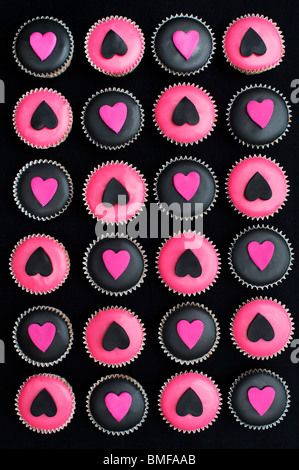 Mini Tortine decorate con nero e rosa ghiaccio e forme di cuore Foto Stock