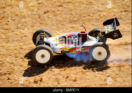 Un modello di vettura da corsa in accelerazione che si allontana da un salto su una pista sterrata. La sfocatura in movimento su ruote. Foto Stock